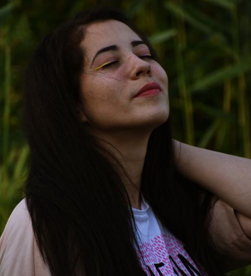 Woman in a peaceful yoga pose against a dark background with sage green light.